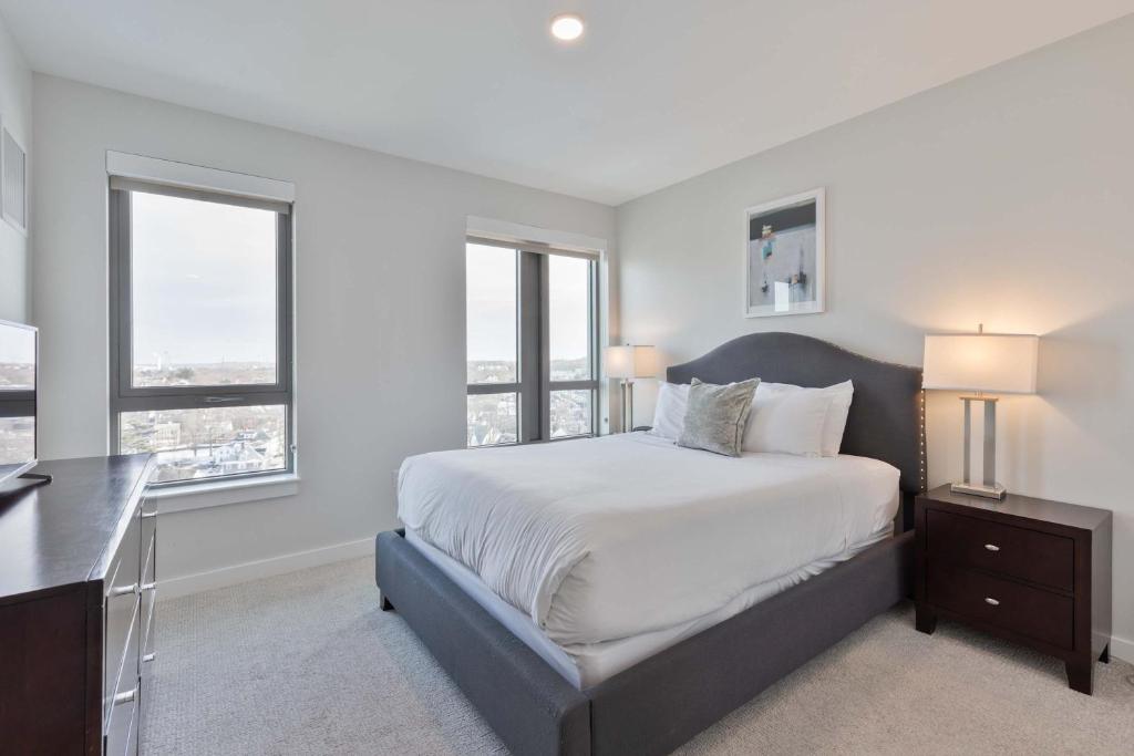 a white bedroom with a large bed and two windows at Private Apt Downtown in Quincy