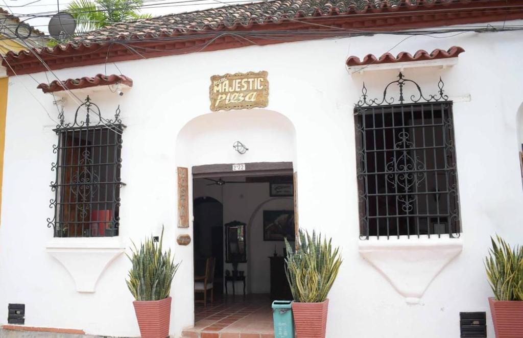 a white building with two windows and plants in front at Hotel Majestic plaza in Mompós