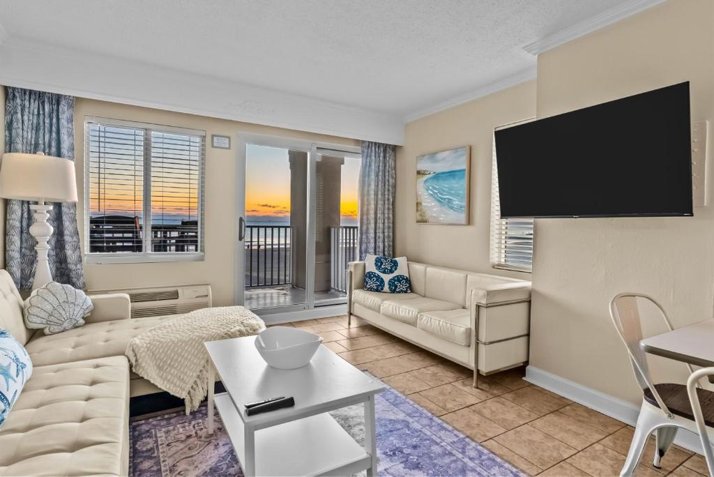 a living room with a couch and a flat screen tv at New / Oceanfront Beach Condo, Pool, Gym, Fishing in Virginia Beach