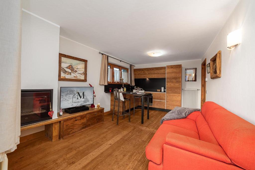 a living room with an orange couch and a television at Maison Carrel Elegant 8 in Breuil-Cervinia