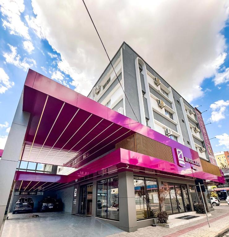 a large building with a purple facade on a street at Hotel Zata e Flats in Criciúma