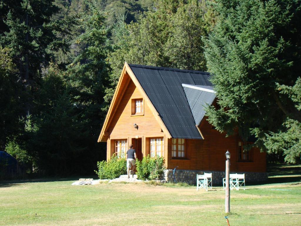a man standing in front of a house with a solar roof at Complejo Aiken in Villa Traful