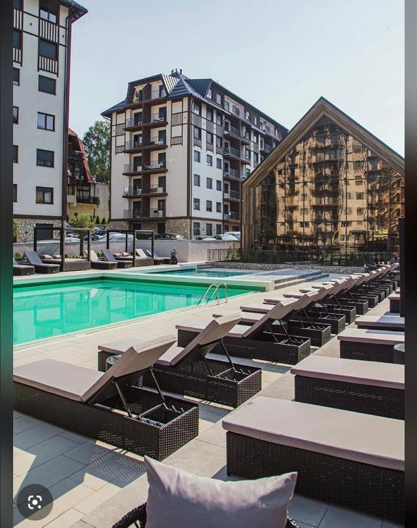a swimming pool with lounge chairs and a building at Aria lux Titova vila in Zlatibor