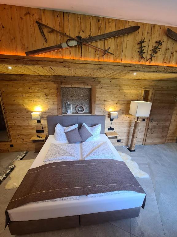 a bedroom with a large bed with wooden walls at Wellness Chalet Apartment Hochkalter in Bischofswiesen