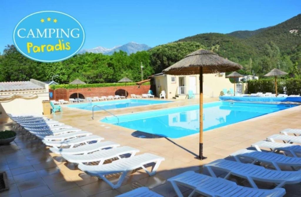 a swimming pool with lounge chairs and an umbrella at ZEcamping 3 animaux acceptés club enfant piscine chauffée in Arles-sur-Tech