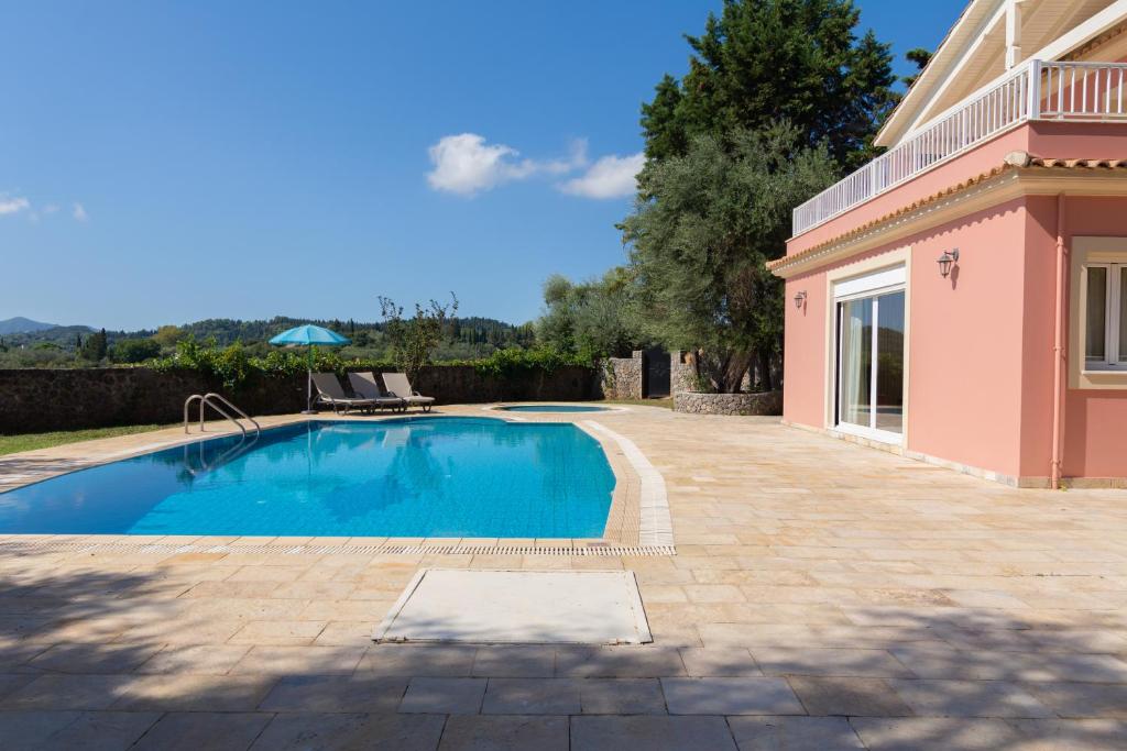 a swimming pool in a yard next to a house at Villa Olympic Azure with Private Pool in Dassia