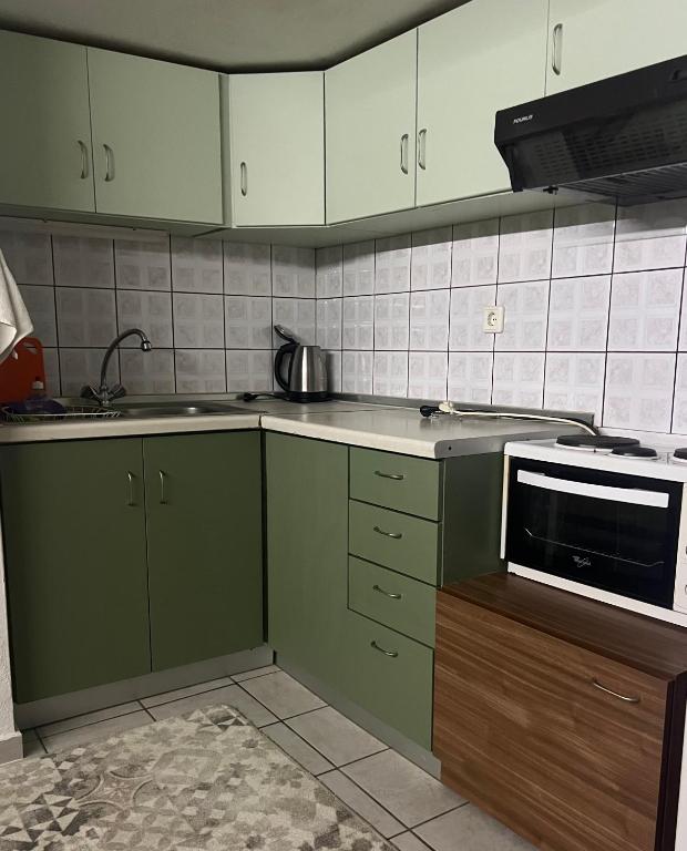 a kitchen with green cabinets and a microwave at Antonioy Apartment Kalampaka in Kalabaka