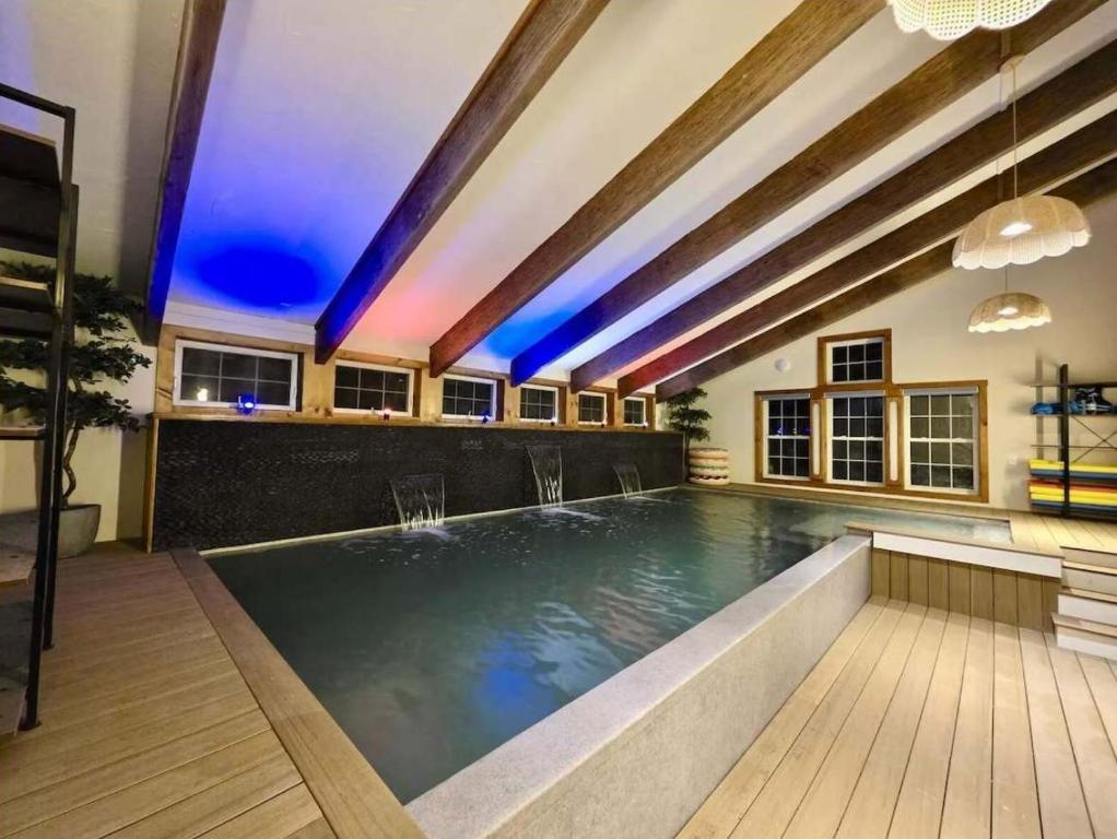 a swimming pool in a building with blue lighting at Myrtle Villa 7BR Near Mount Snow with Indoor Heated Endless Style Pool Outdoor Hot Tub in Dover