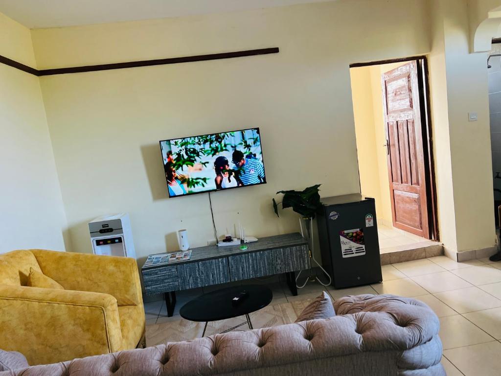 a living room with a couch and a tv on the wall at Figtree 1bedroom by kiv in Kilifi