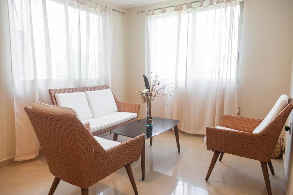 a living room with a white couch and chairs and a table at Newly renovated apartment with pool in Santa Cruz Huatulco