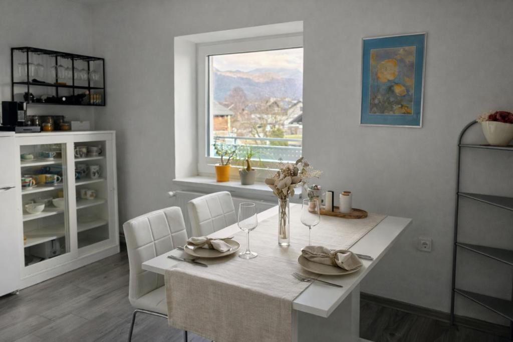 a white dining room with a table and a window at Apartment Čebelica in Lesce