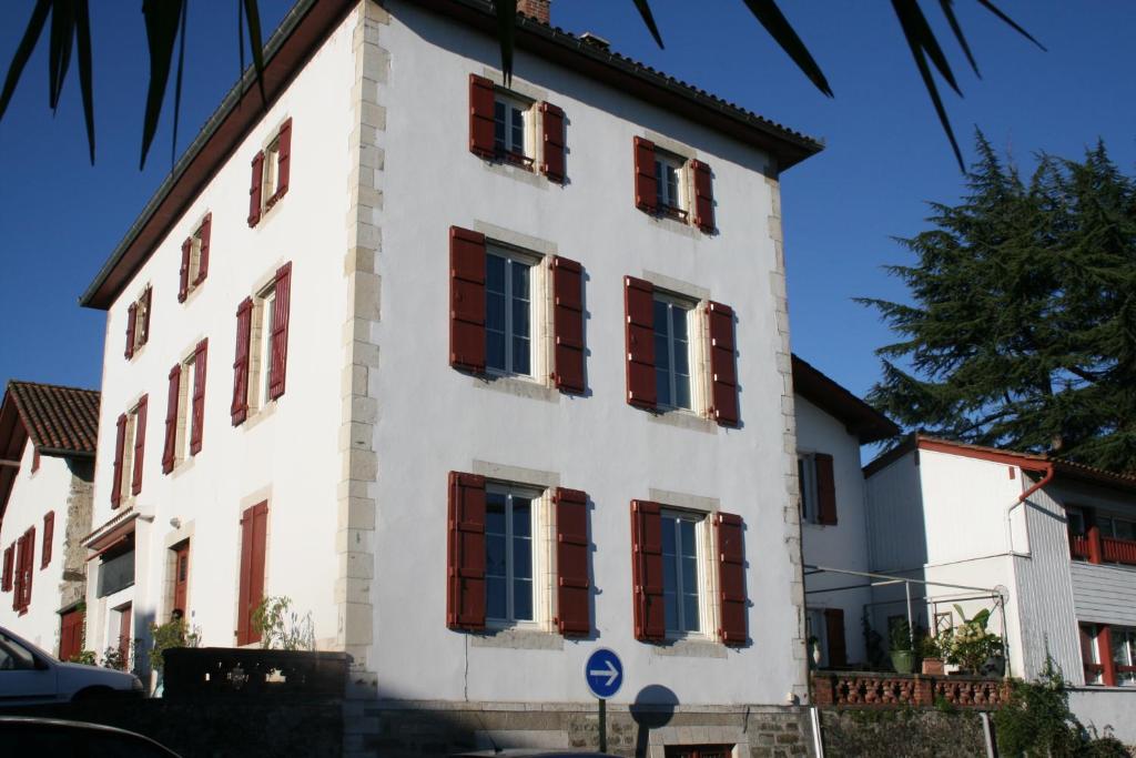 um edifício branco com janelas vermelhas com persianas em Chambres d'Hôtes Ene Gutizia em Ustaritz