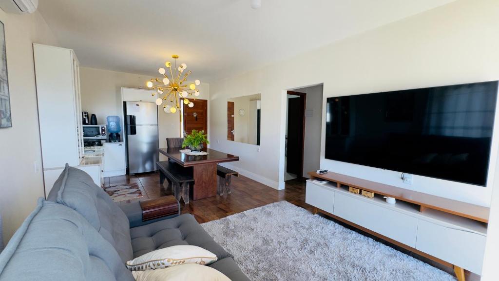 a living room with a couch and a large flat screen tv at Jardim dos Ipês in Araranguá
