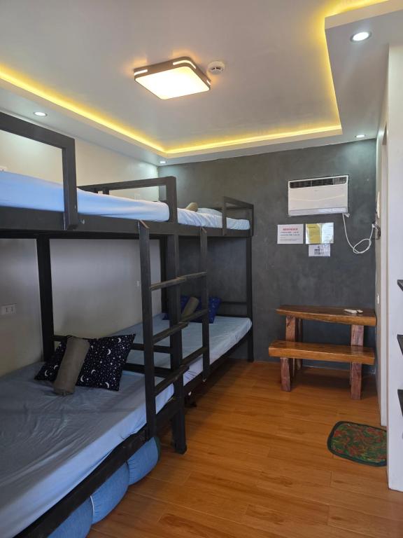 a room with three bunk beds and a table at Aloha Aina Dive Resort in Mabini