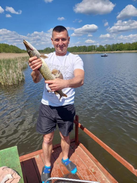 a man standing on a boat holding a fish at Perła Brenno in Brenno