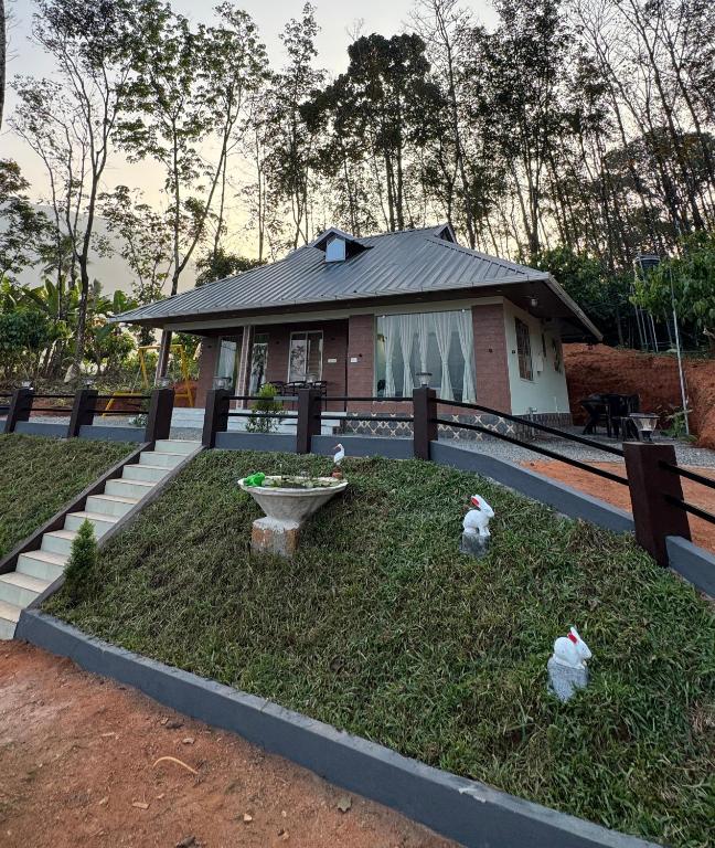 a house with a yard with two chickens in the grass at Riverfolk Stays in Thodupuzha