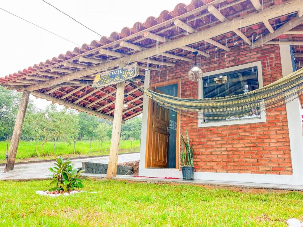 a brick building with a sign in front of it at Chalé Flor de Ypê in Carrancas
