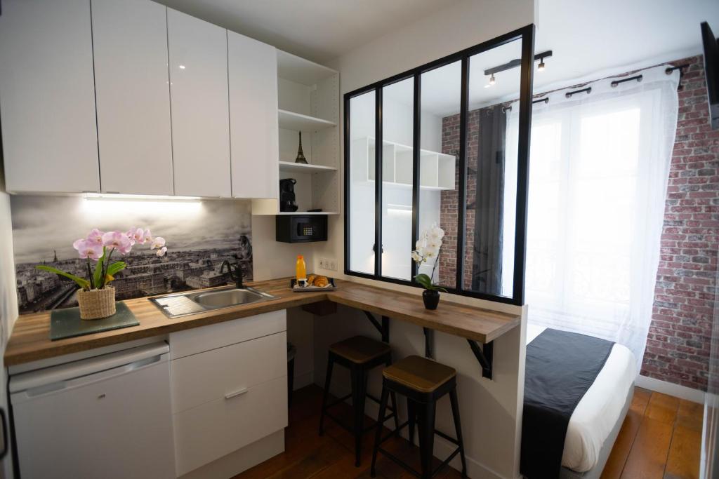 a kitchen with white cabinets and a counter with a sink at Beatrice et Emmanuel Meublé Eiffel in Paris