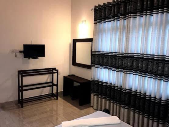 a room with a television and a table with a mirror at Madusanka Holiday Home in Gomagoda