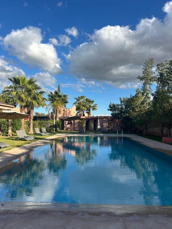 a large swimming pool with palm trees in the background at Private pool villa & garden Marrakech in Marrakesh