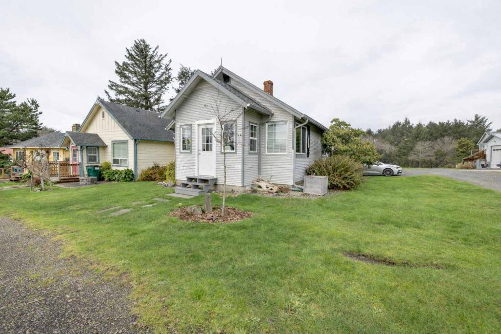 a white house with a yard with a house at Coho Cottage in Rockaway Beach