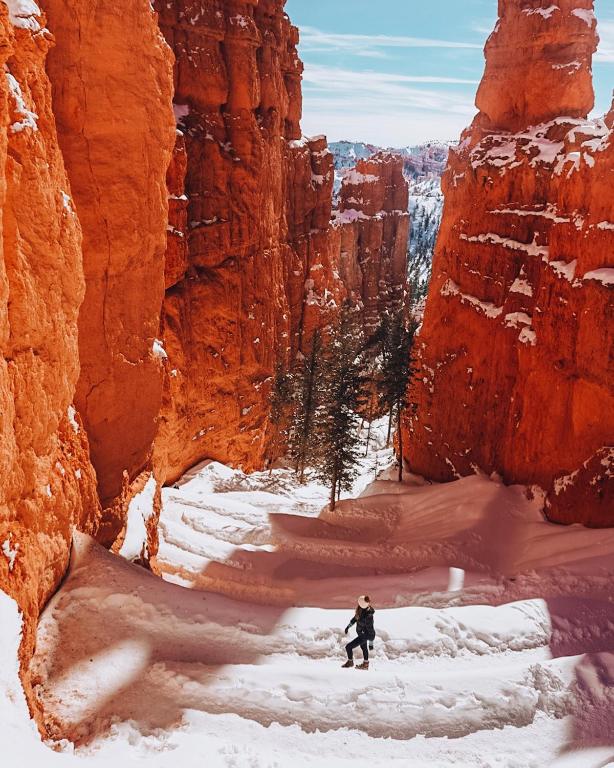 a person walking through a canyon in the snow at Bryce Canyon Escalante Glamping in Cannonville