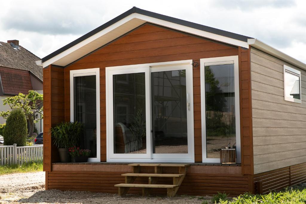 a tiny house with a porch and a staircase at Hof Eichendiek Time Out Village- Haus Naturruhe in Blekendorf