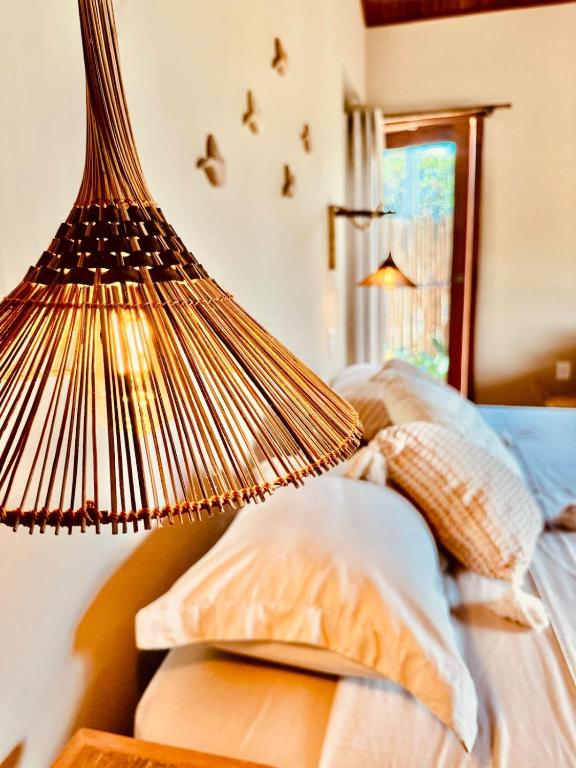 a lamp on top of a bed with pillows at Chalé Caju Knots in Parajuru