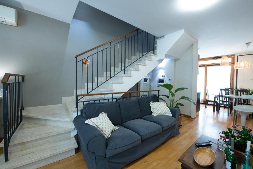 a living room with a blue couch and a staircase at Egea Beach House in Lido di Camaiore