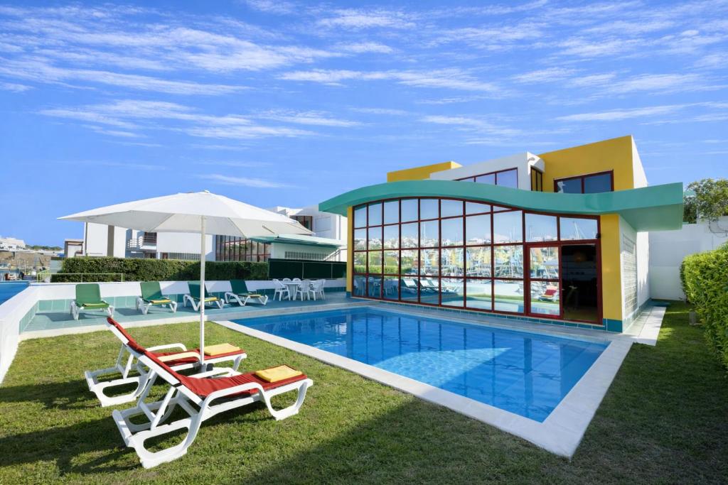 a villa with a swimming pool and two chairs and an umbrella at Marina - Private Pool - 10 Pax - Albufeira in Albufeira