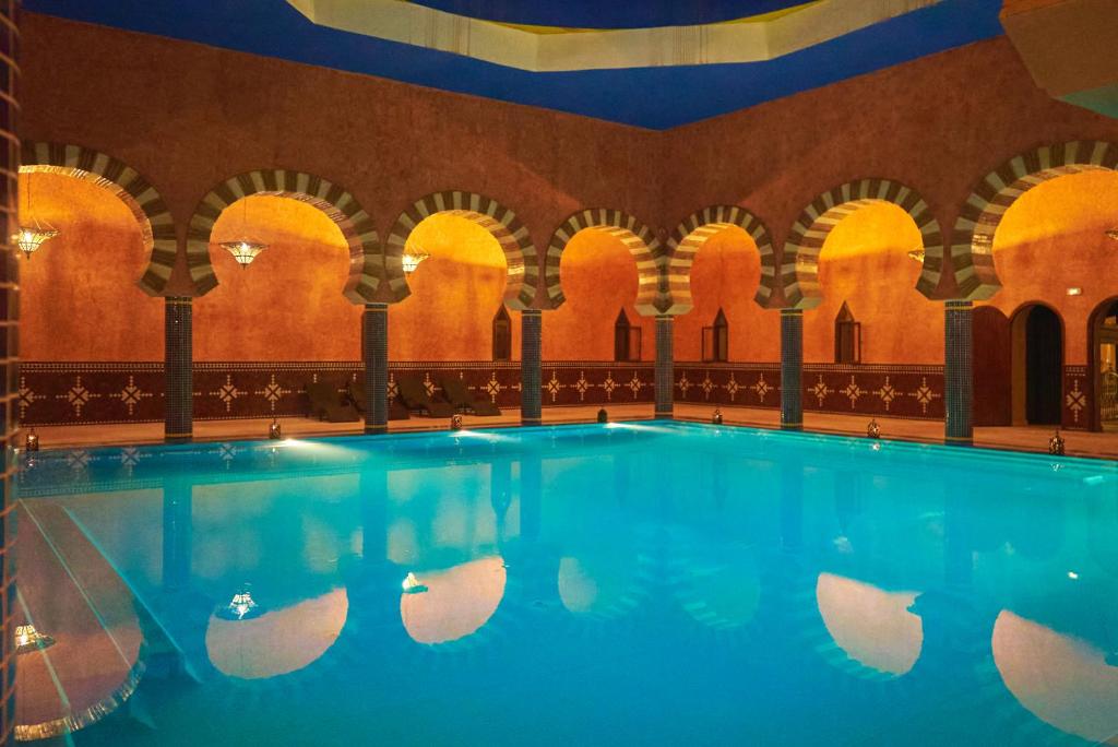 a large swimming pool in a building with arches at Hotel Kasbah Azalay in Mhamid