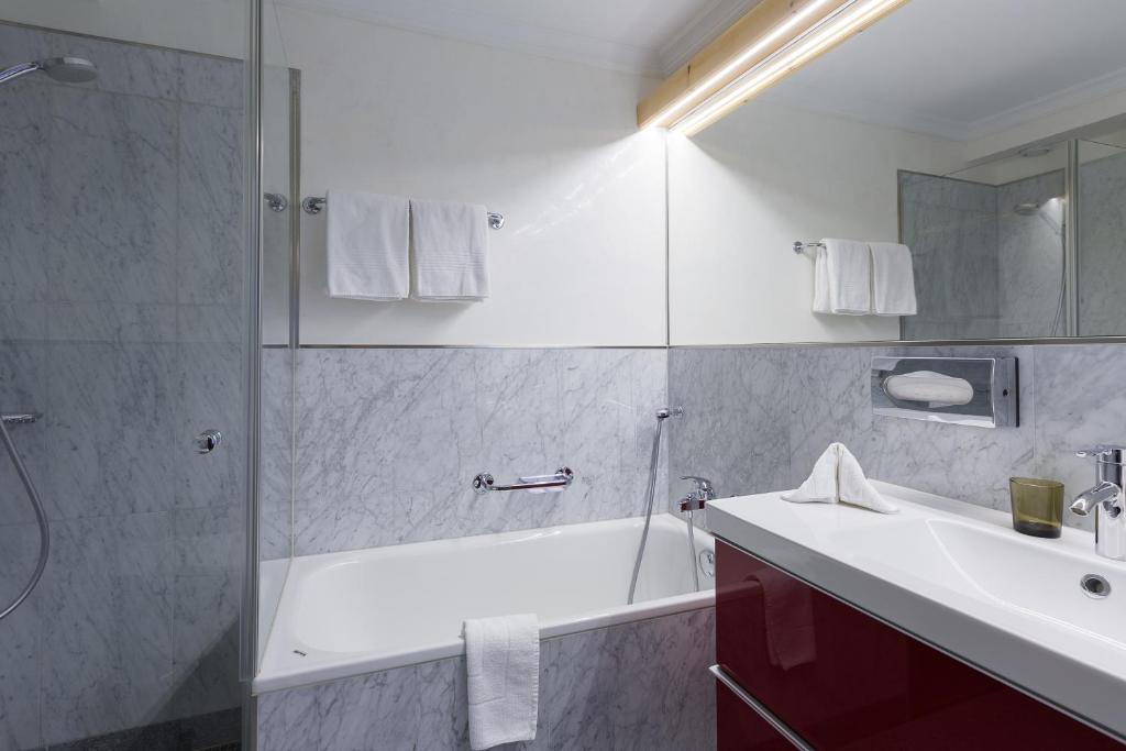 un bagno con vasca, lavandino e doccia di Hotel Nolda a Sankt Moritz