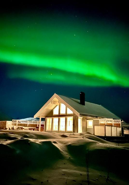a building with the aurora in the sky at Hytte ved havet på Brensholmen, nær Sommarøy, Tromsø in Tromsø