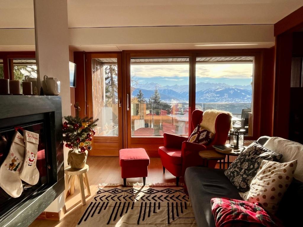 a living room with a fireplace and a large window at Renovated Apartment 5 min to Crans Montana Center in Crans-Montana