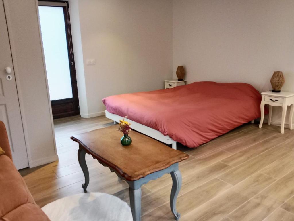 a bedroom with a red bed and a table at Studio nature indépendant in Le Gâvre