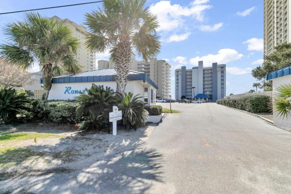 a street with palm trees and a sign in front of a building at Romar Tower 5C in Romar Beach