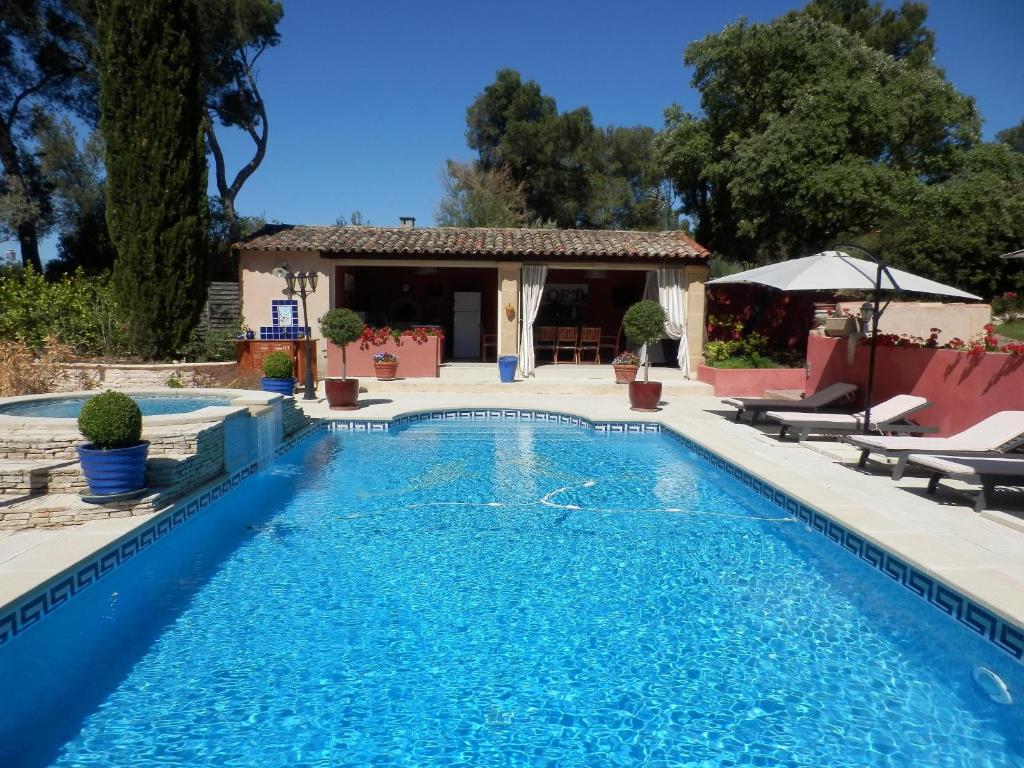 a swimming pool with chairs and a house at Mas les vieux chênes in Lambesc