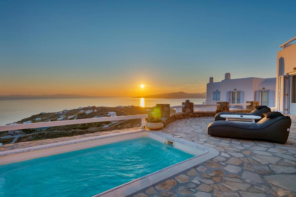a pool with a couch and a reclining chair next to a sunset at Boutique Villa Aquata Private pool in Mikonos