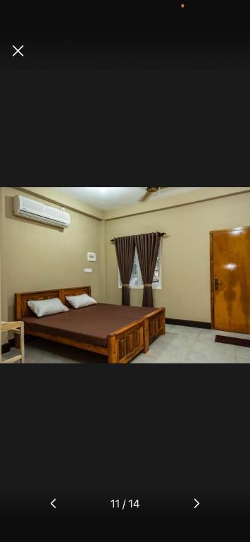 a bedroom with a wooden bed and a window at Abbi Holiday Service Apartment in Jaffna