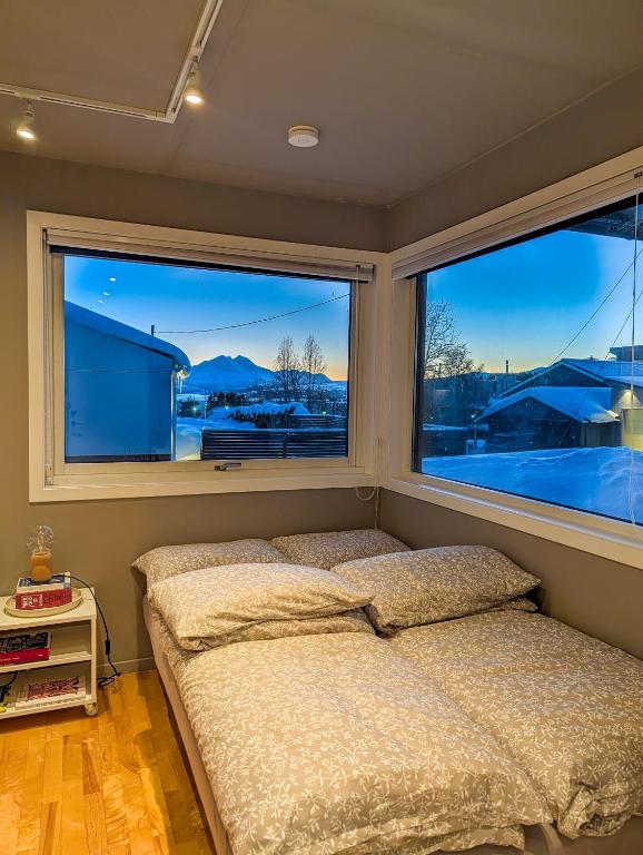 a bed in a bedroom with two large windows at Private Studio with Bathroom and Kitchen, Central Location in Tromsø