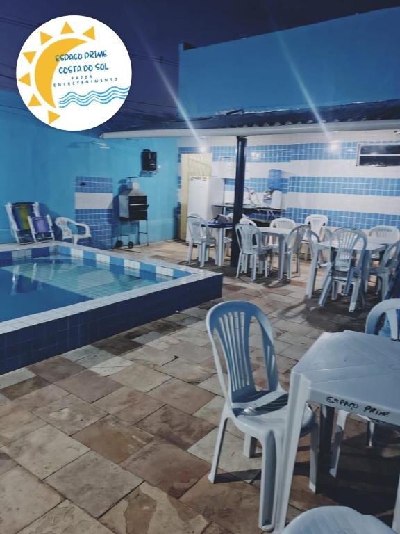 a pool with chairs and a table next to a swimming pool at Casa de temporada 08 Pessoas PISCINA LAZER Entretenimento pra família in João Pessoa