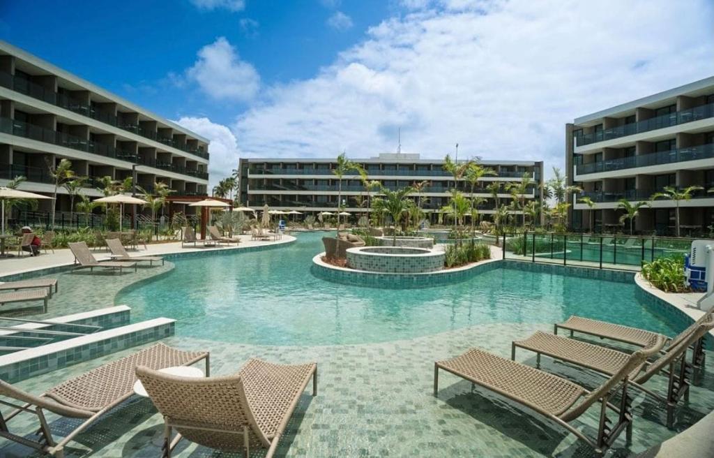 a swimming pool with chairs and a hotel at Luxury Flat with Breakfast! in Ipojuca