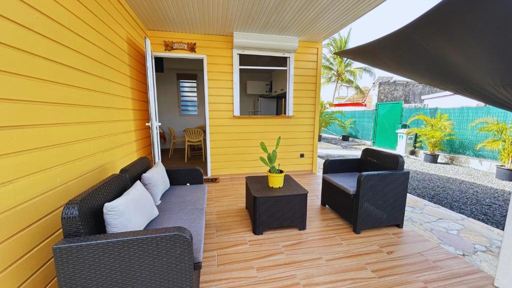 a yellow house with two chairs and a table at Bungalow Soleil Sainte-Anne - Plage à pied in Sainte-Anne