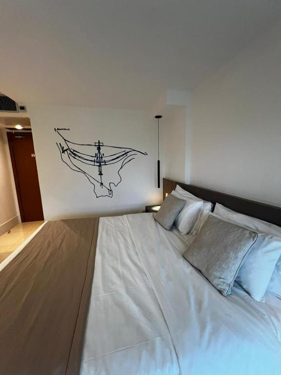 a bedroom with a large white bed with a drawing on the wall at Ap Tryp by Wyndham Nações in Brasília