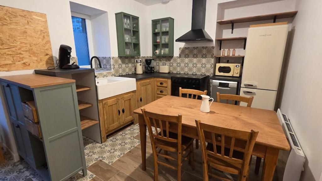 a kitchen with a wooden table and a sink at Maison Ty Bian Prieuré in Pleubian