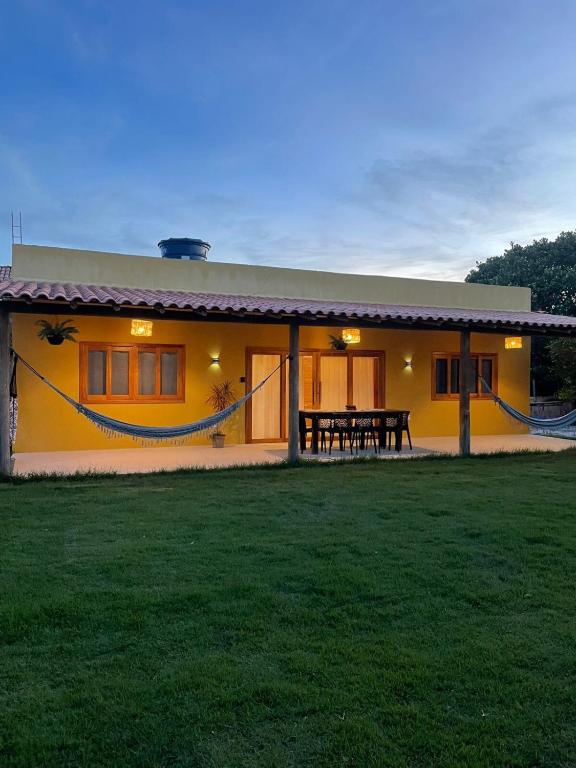 a yellow house with a picnic table in front of it at Casa Refúgio do Rio in Caraíva