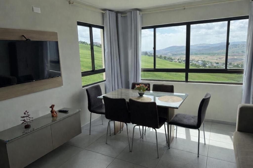 a dining room with a table and chairs and a large window at Domaine Residence in Gravatá