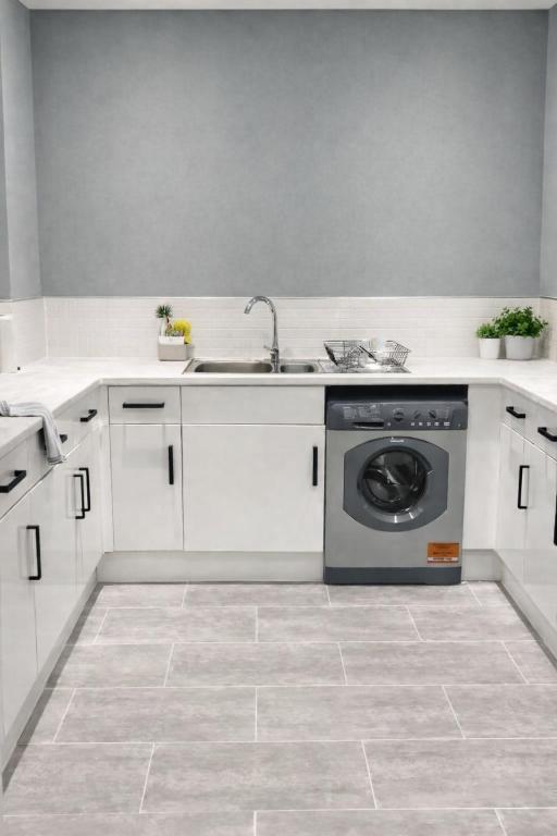 a kitchen with a sink and a washing machine at Spacious 2 Bed Apartment with Free Parking, Sleeps Up To 6 in Purley