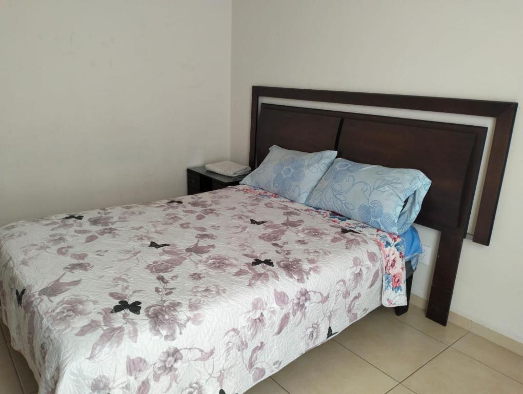 ein Bett mit geblümter Bettdecke und zwei Kissen in der Unterkunft Hotel Morelia Nova in Morelia
