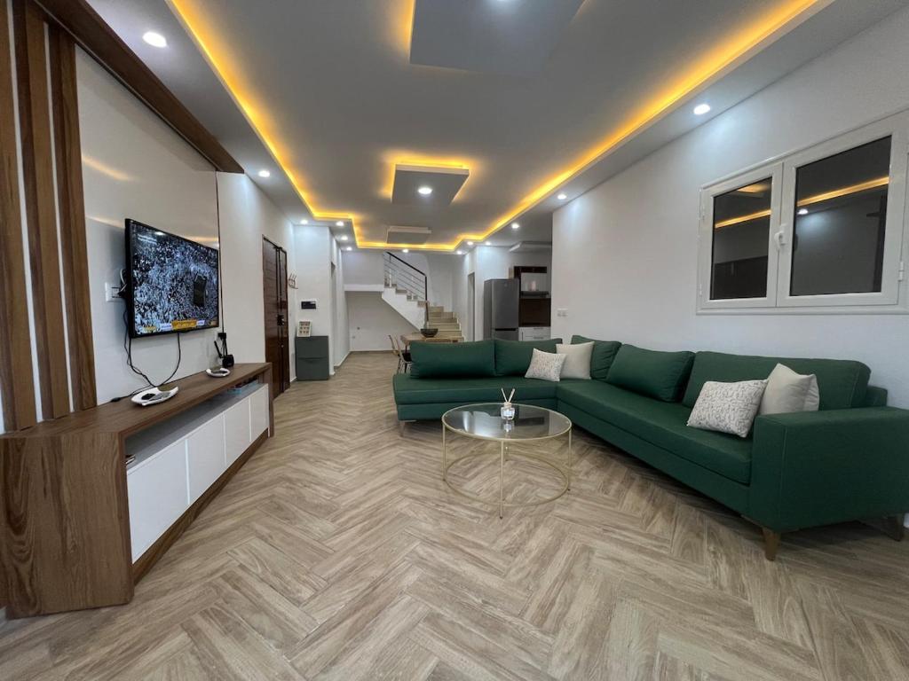 a living room with a green couch and a tv at Maison des 5 palmiers in Taguermess